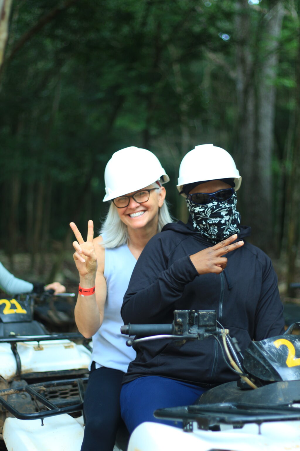 Two women in helmets making peace signs on an ATV