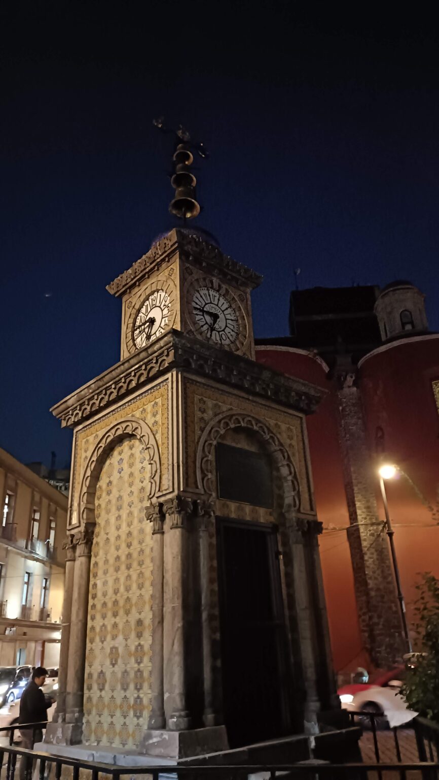 Ornate clock tower lit up at night in downtown Mexico City