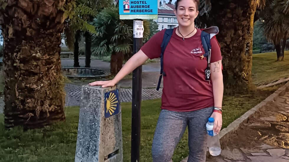 Hannah by Camino de Santiago trail signs under palm trees