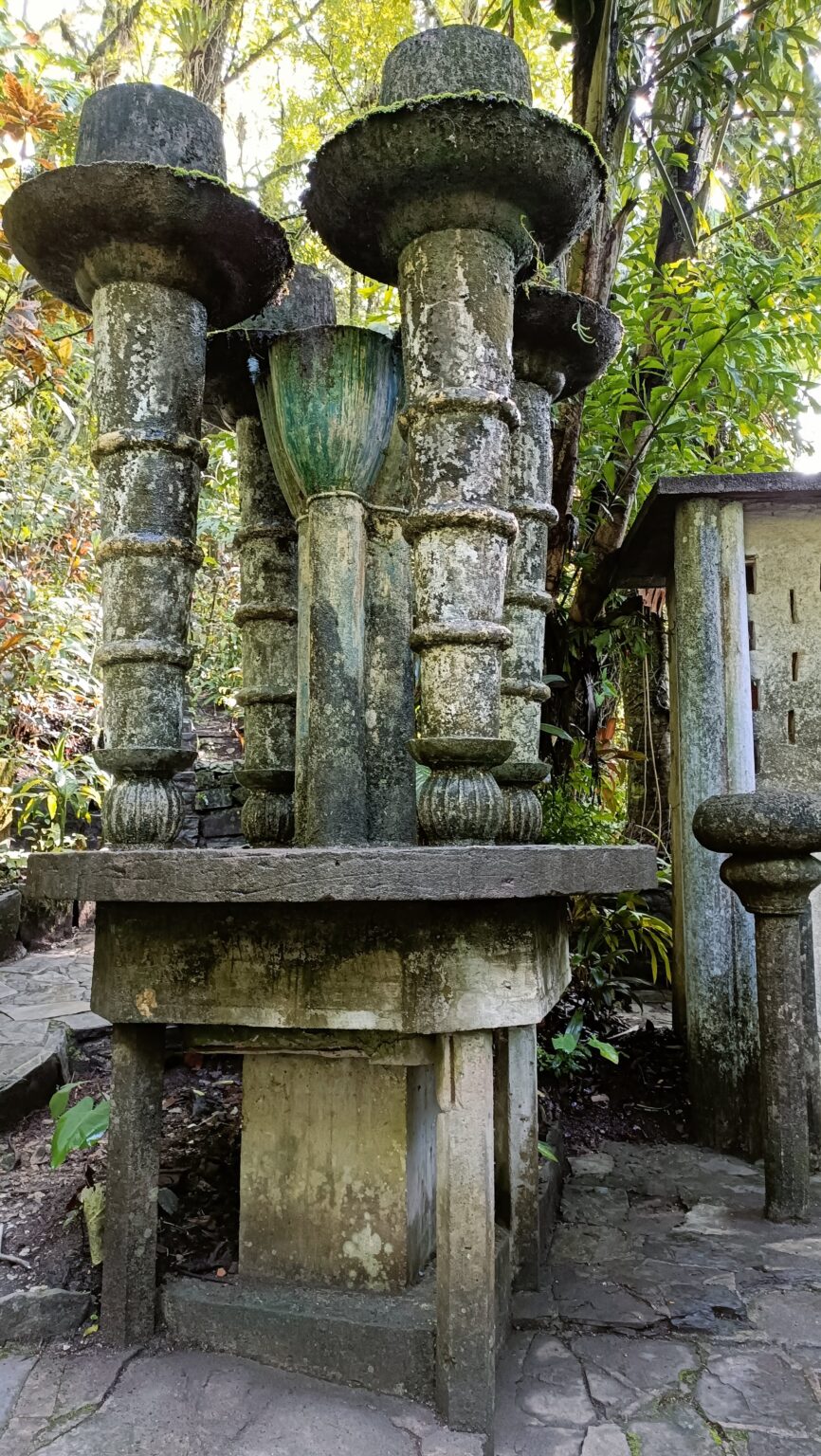 Carved concrete columns and a throne-like sculpture at Las Pozas