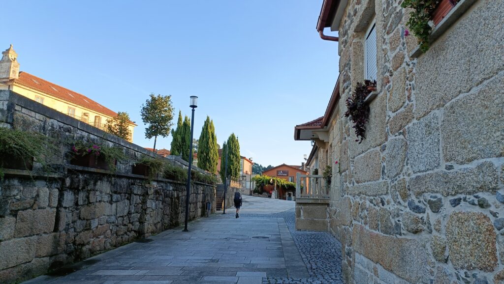 person walking between houses with hiking equipment