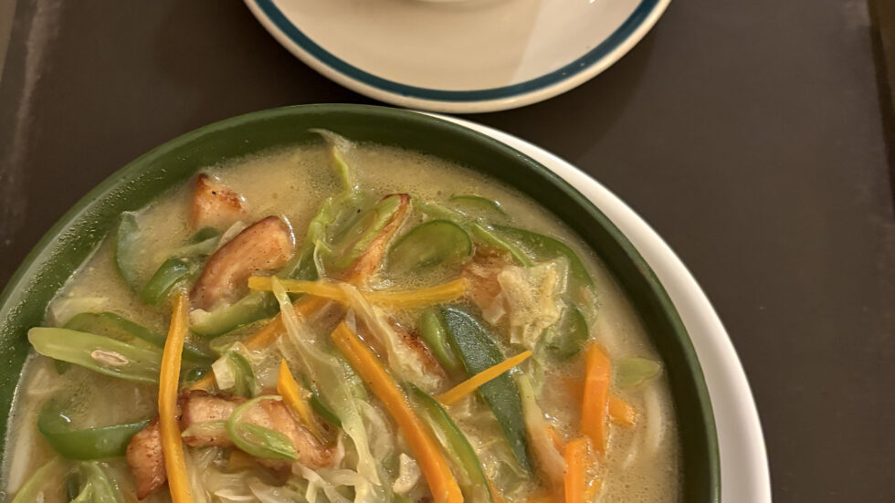 Bowl of vegetable noodle soup and a cup of milk tea in Pokhara