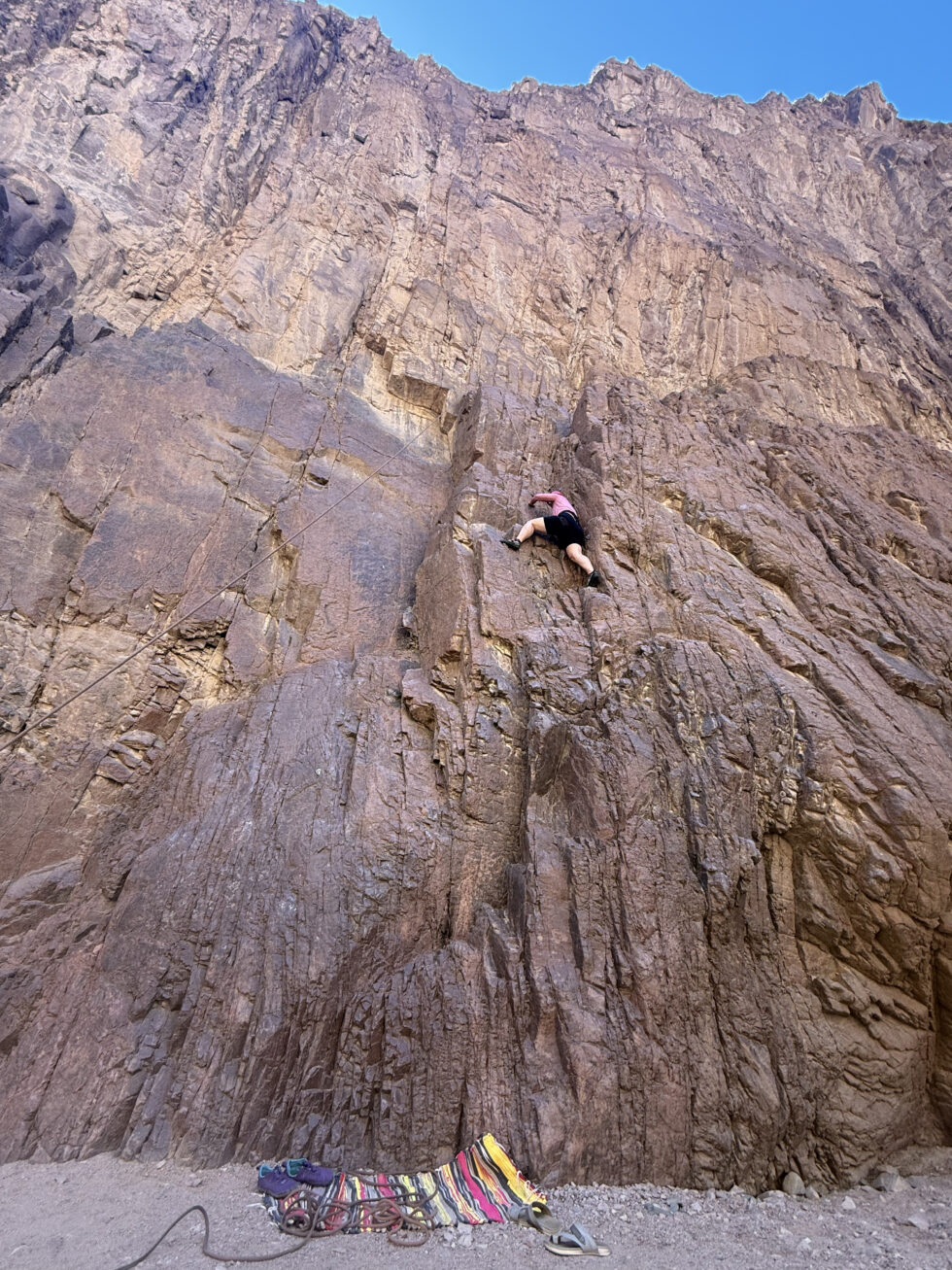 Climber scaling a tall rock face in the Sinai desert near Dahab