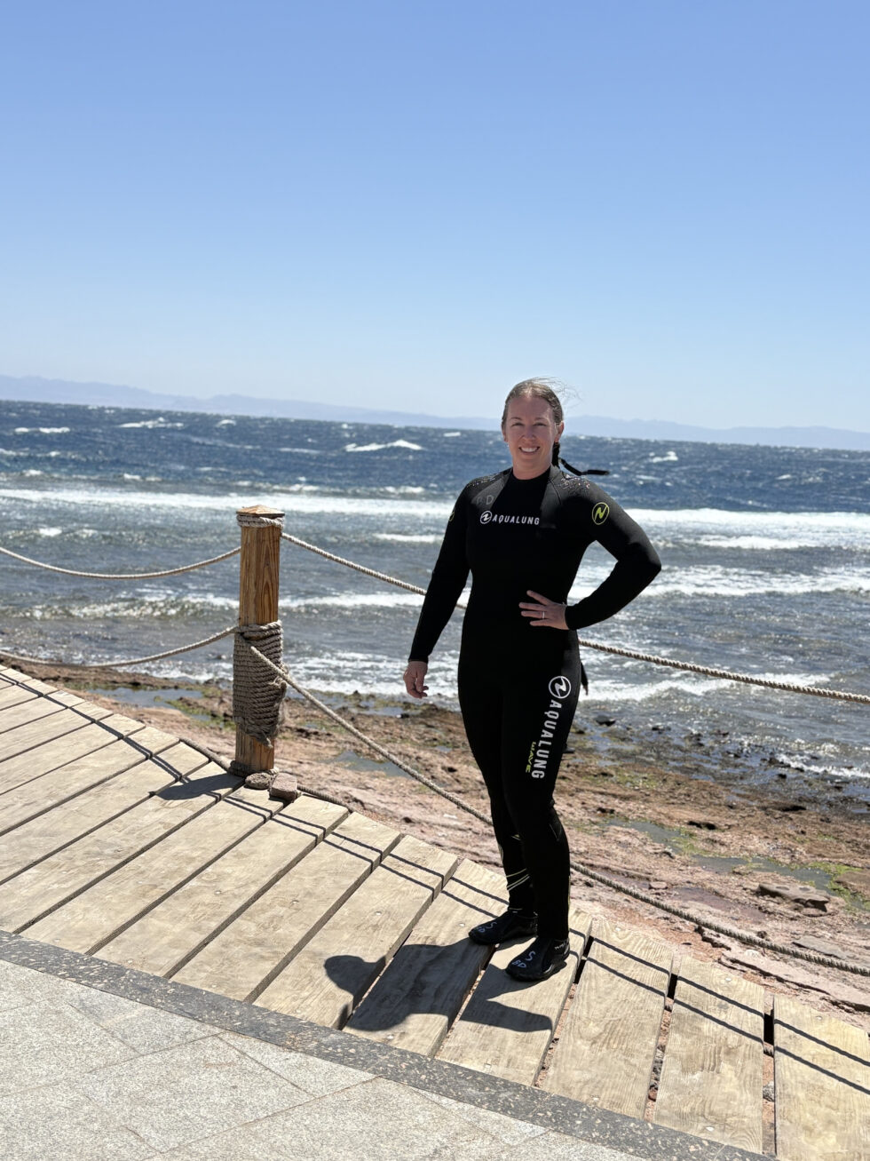 Hannah in a wetsuit on a boardwalk by the Red Sea in Dahab