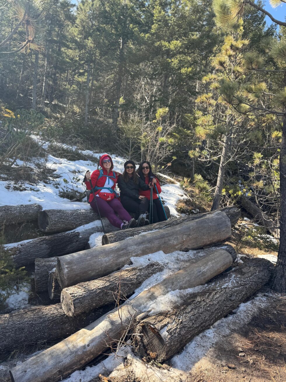 Hikers resting on logs beside patches of snow on the La Marta trail