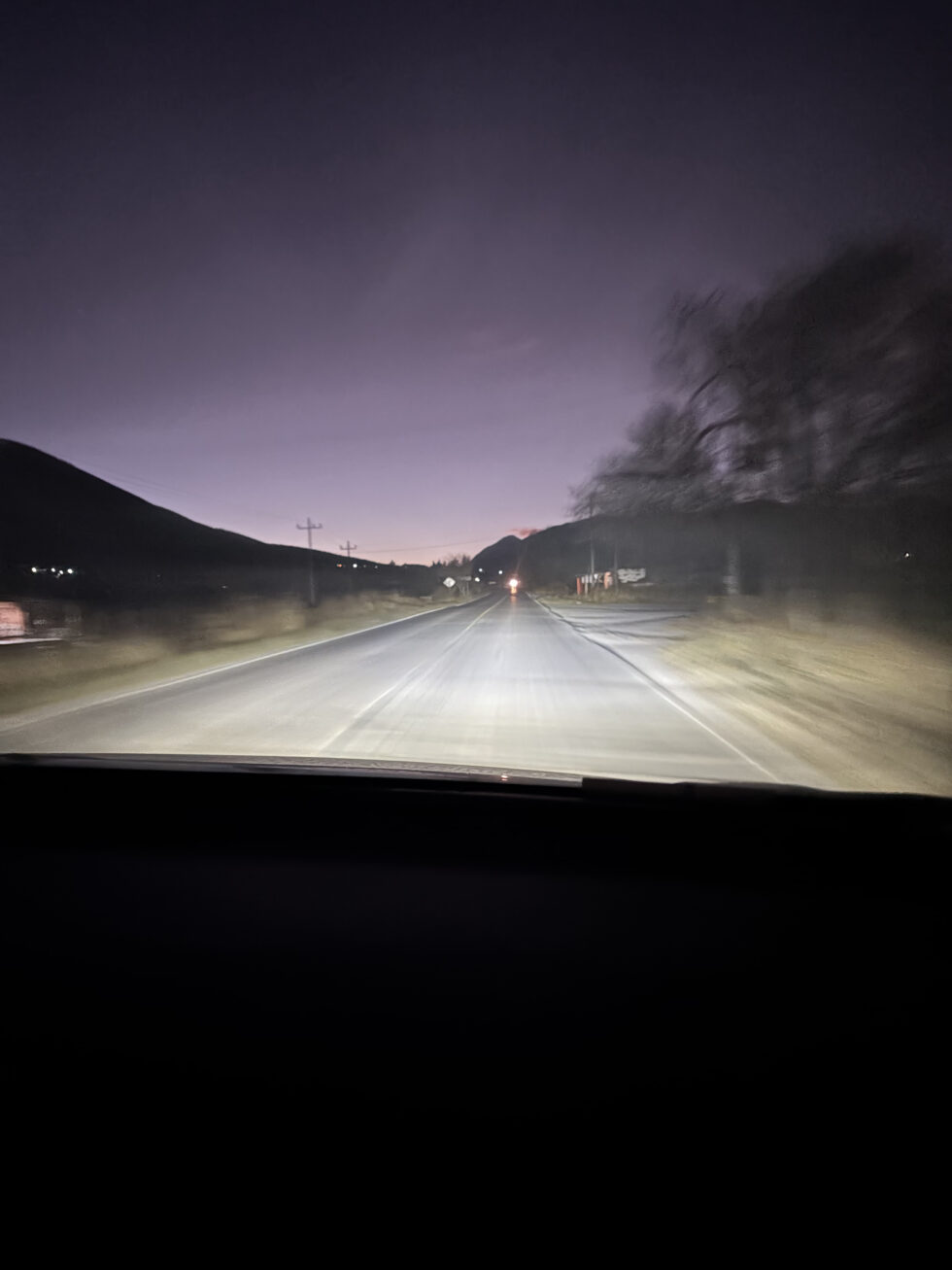 Headlights on a dark road during the early morning drive to La Marta