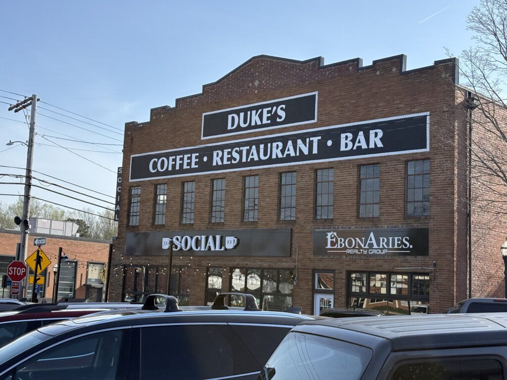 The brick Duke's building on a Leonardtown corner, its old sign reading Duke's Coffee Restaurant Bar with Social below it.