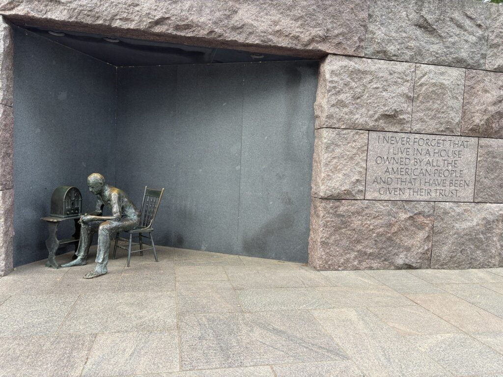 A bronze sculpture of a seated man in a stone alcove at the FDR Memorial