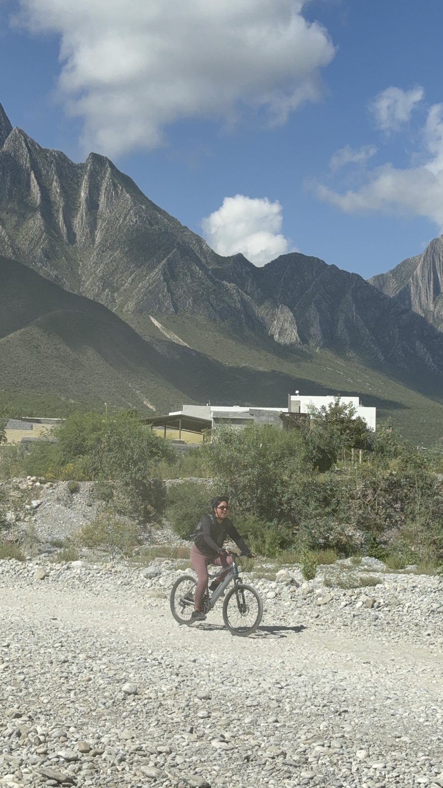 A cyclist on a gravel road below the cliffs of La Huasteca