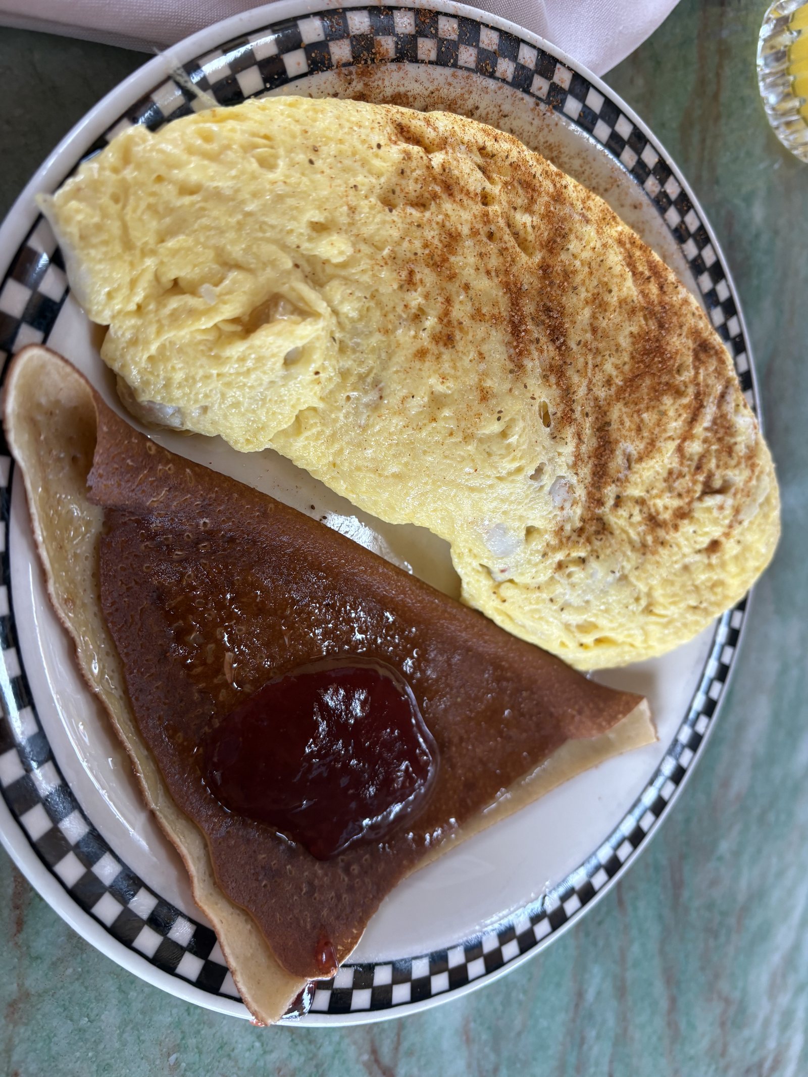 A breakfast plate with an omelette, a fried slice of scrapple and a spoonful of jelly