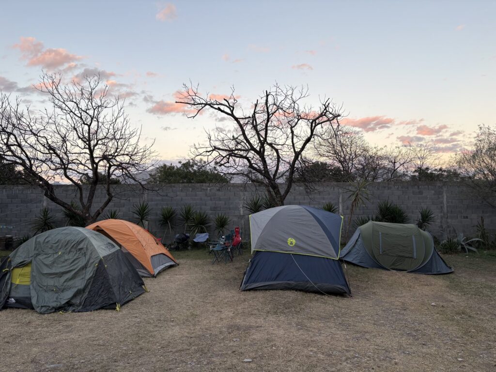 Tents pitched inside a walled campground at dusk near El Potrero Chico