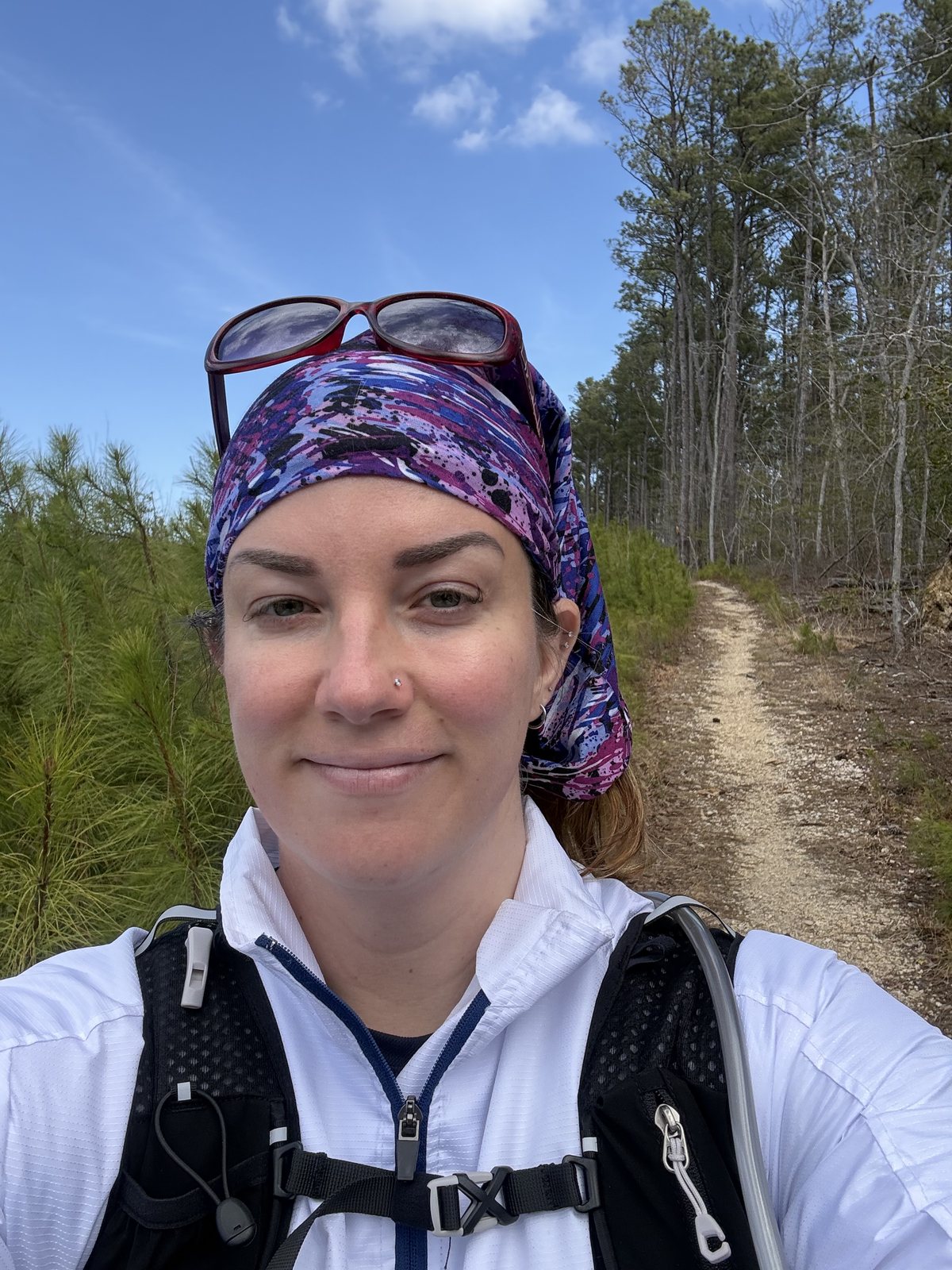 A hiker in a purple bandana on the sandy trail at St Mary's River State Park in Maryland in March