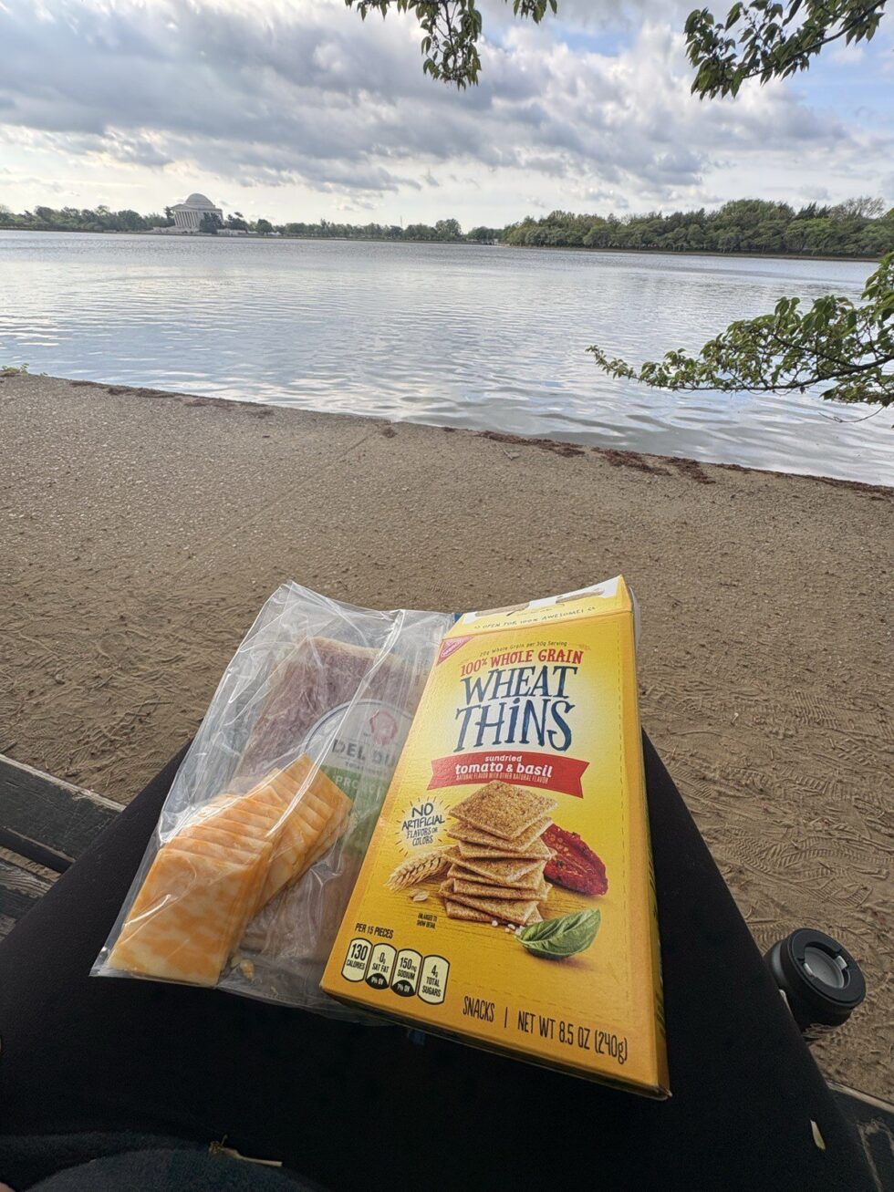 A picnic of Wheat Thins and snacks on the Tidal Basin shore with the Jefferson Memorial across the water